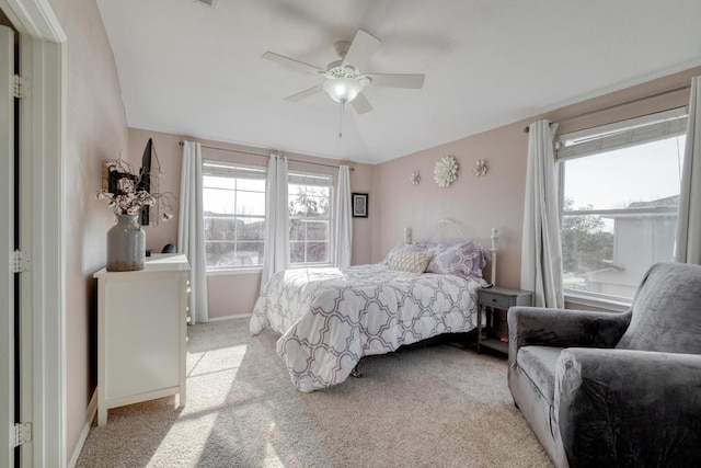 bedroom featuring light carpet, multiple windows, vaulted ceiling, and a ceiling fan