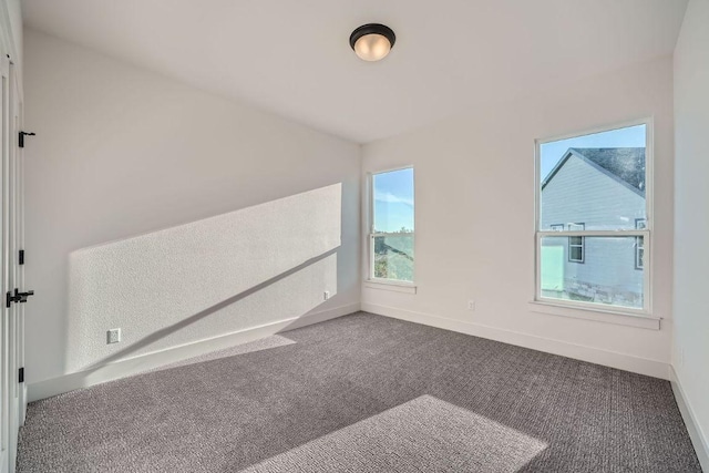 bonus room featuring dark carpet and baseboards