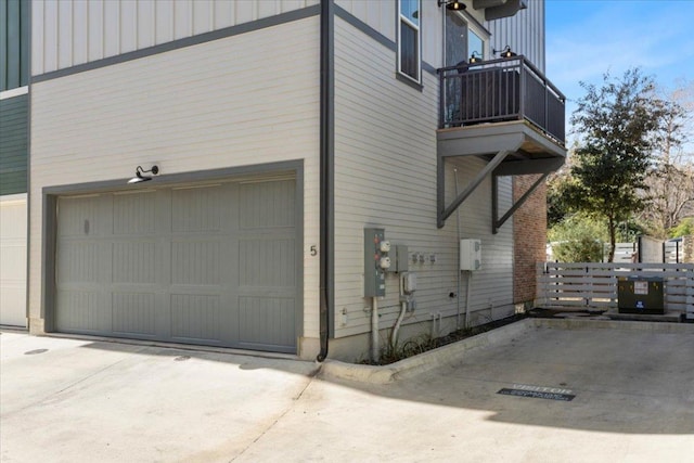 view of property exterior with board and batten siding, driveway, a balcony, and a garage