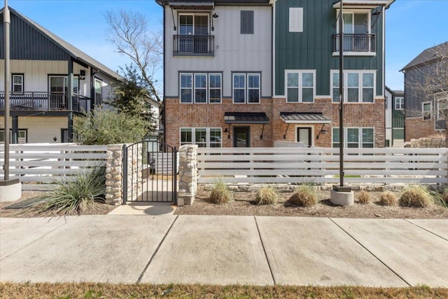 multi unit property with a fenced front yard, a gate, and brick siding