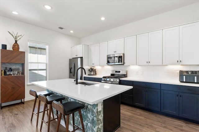 kitchen featuring a breakfast bar, a sink, appliances with stainless steel finishes, tasteful backsplash, and an island with sink