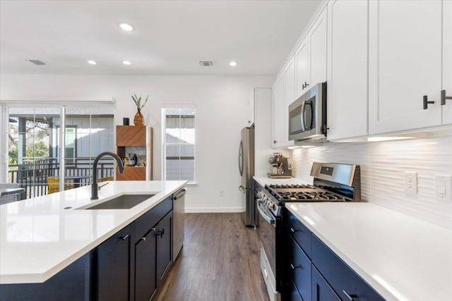 kitchen with a sink, white cabinetry, light countertops, appliances with stainless steel finishes, and decorative backsplash