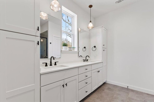 full bath with a sink, visible vents, baseboards, double vanity, and a stall shower