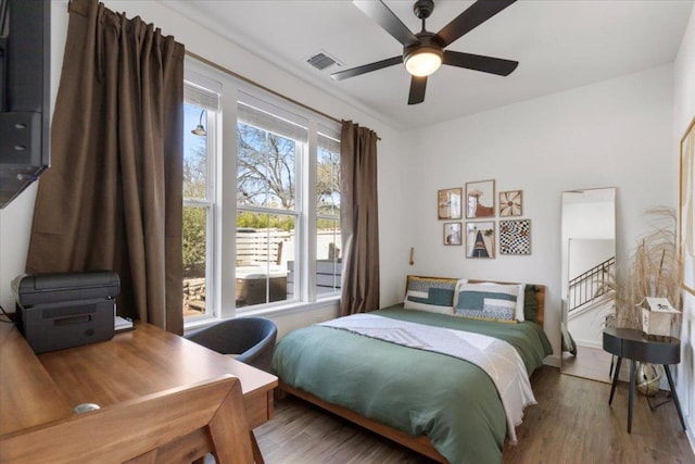 bedroom featuring baseboards, ceiling fan, visible vents, and wood finished floors