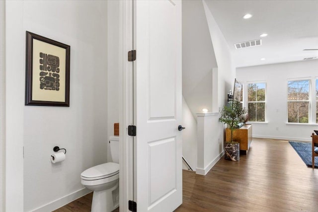 bathroom with toilet, wood finished floors, visible vents, and baseboards