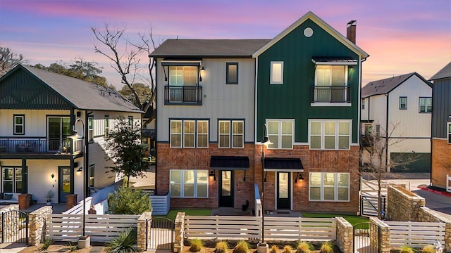 multi unit property with a balcony, a fenced front yard, a gate, and a chimney