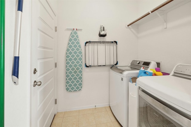 laundry room with laundry area, washer and clothes dryer, baseboards, and light tile patterned floors