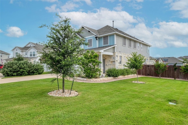 view of front of property with driveway, a front lawn, stone siding, and fence