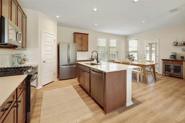 kitchen with stainless steel appliances, light wood-type flooring, a sink, and visible vents