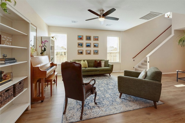 living room featuring plenty of natural light, stairway, light wood-style flooring, and visible vents