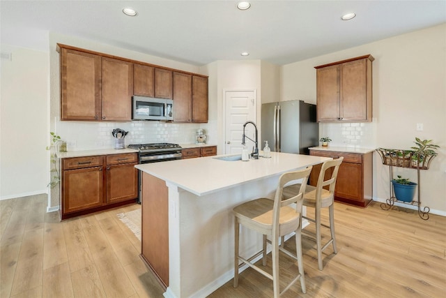 kitchen with brown cabinets, light wood-style flooring, and stainless steel appliances