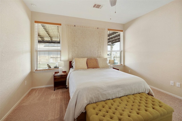 carpeted bedroom featuring baseboards, visible vents, a ceiling fan, and a textured wall