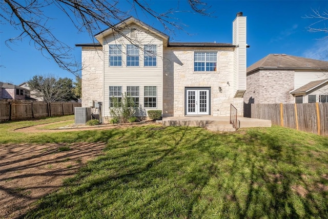 rear view of property with a lawn, a fenced backyard, a chimney, french doors, and a patio area