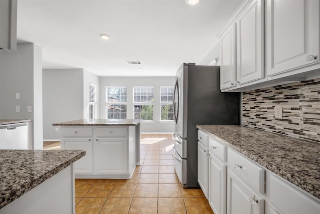 kitchen featuring light tile patterned floors, dishwashing machine, white cabinetry, light stone countertops, and tasteful backsplash