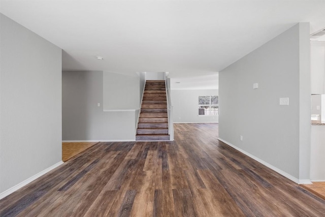 unfurnished living room with baseboards, stairway, and wood finished floors