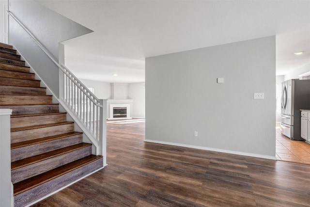 stairway with a glass covered fireplace, baseboards, and wood finished floors