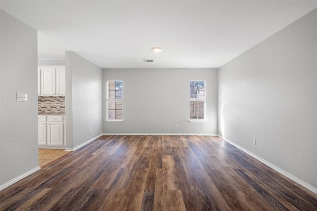 spare room featuring wood finished floors, visible vents, and baseboards