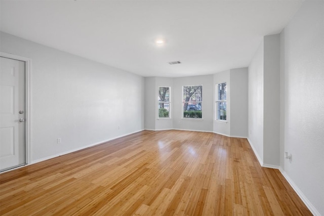 spare room with light wood-style floors, visible vents, and baseboards