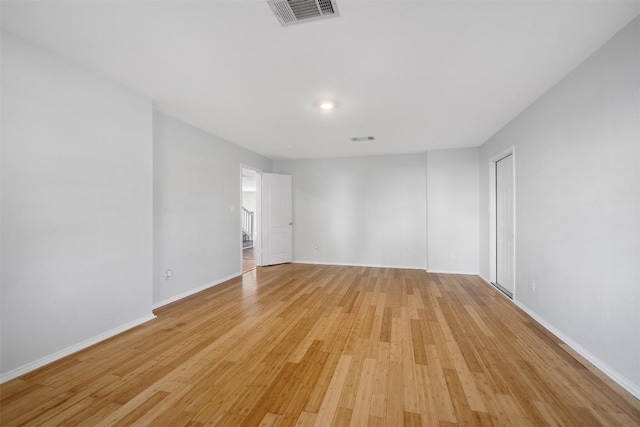 empty room featuring light wood-style floors, baseboards, and visible vents