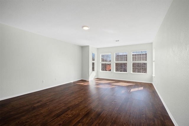 empty room with visible vents, baseboards, and wood finished floors