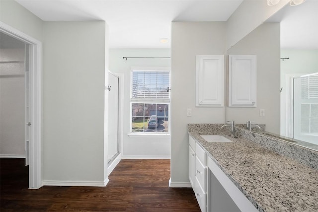 bathroom with a shower stall, baseboards, wood finished floors, and vanity