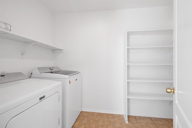 clothes washing area featuring laundry area, light tile patterned floors, baseboards, and separate washer and dryer