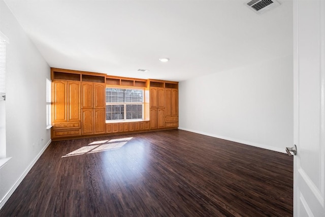 spare room featuring dark wood-style flooring, visible vents, and baseboards