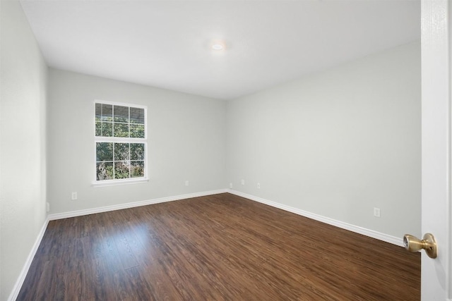 unfurnished room with dark wood finished floors and baseboards