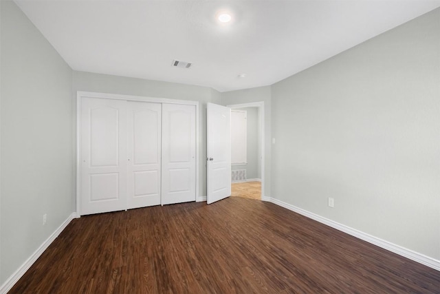 unfurnished bedroom featuring dark wood-style floors, visible vents, and baseboards