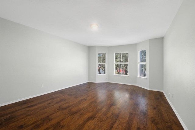 unfurnished room with dark wood finished floors and baseboards