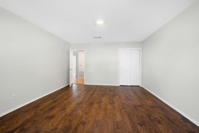 spare room featuring baseboards, visible vents, and dark wood-type flooring