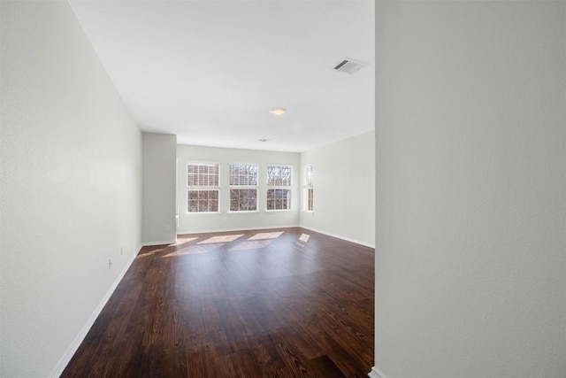 unfurnished room featuring wood finished floors, visible vents, and baseboards