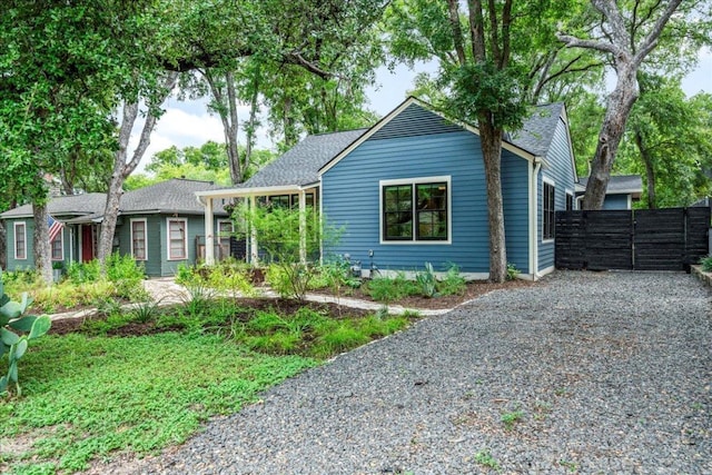 single story home featuring driveway, roof with shingles, fence, and a gate