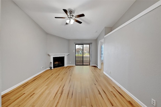 unfurnished living room with light wood-style floors, ceiling fan, a fireplace, and baseboards