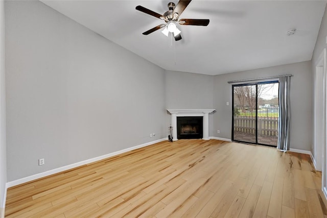 unfurnished living room featuring a ceiling fan, a fireplace with flush hearth, light wood-style flooring, and baseboards