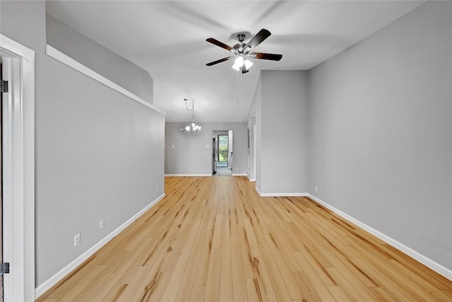 unfurnished living room featuring ceiling fan with notable chandelier, vaulted ceiling, hardwood / wood-style flooring, and baseboards