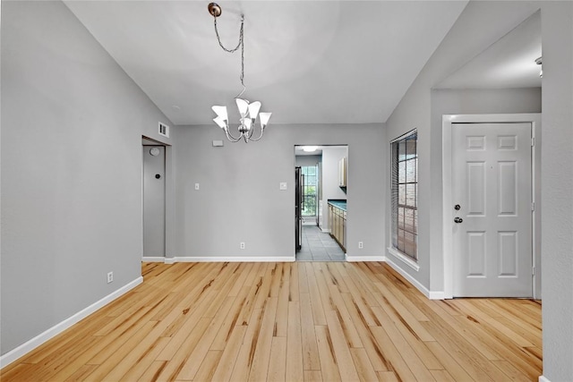 unfurnished dining area with baseboards, a notable chandelier, visible vents, and light wood finished floors