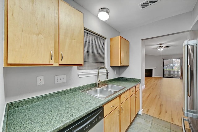 kitchen featuring light brown cabinets, stainless steel appliances, a fireplace, a sink, and visible vents