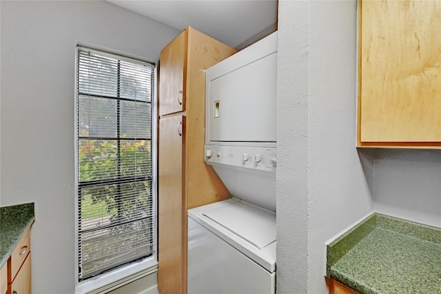 washroom with stacked washer and clothes dryer and cabinet space