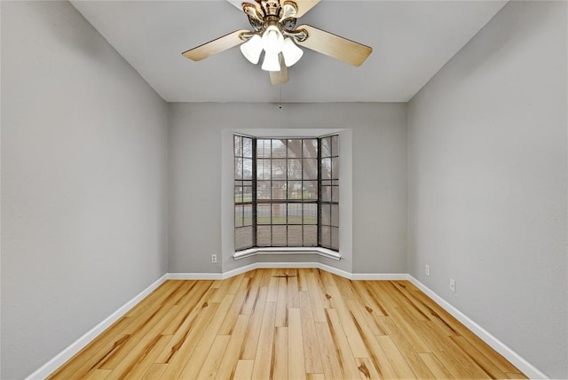 empty room with ceiling fan, baseboards, and wood finished floors