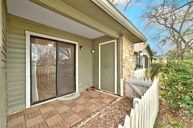 doorway to property featuring brick siding and fence