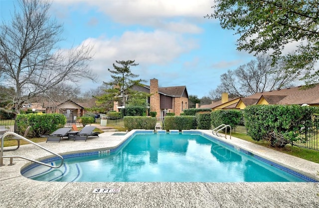 community pool with a patio area and fence