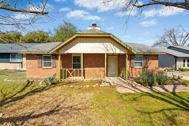 ranch-style house featuring a porch, a front lawn, a chimney, and brick siding