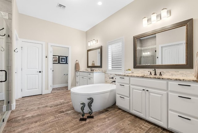 bathroom featuring wood finished floors, a stall shower, a sink, and visible vents