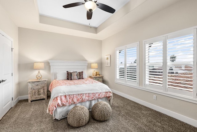 bedroom featuring a ceiling fan, baseboards, a tray ceiling, and carpet flooring