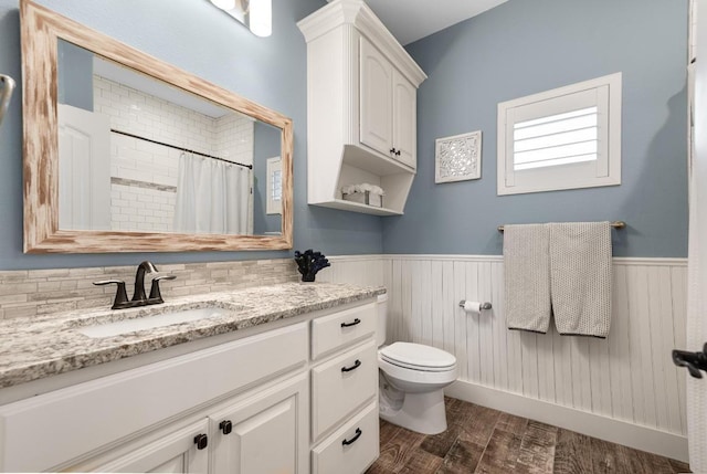 bathroom with toilet, wainscoting, wood finished floors, and vanity