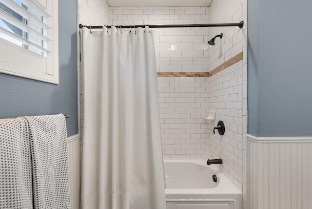 full bath featuring shower / tub combo and a wainscoted wall