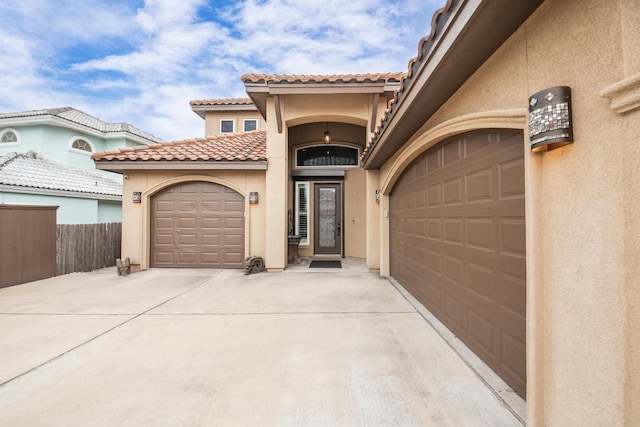 exterior space featuring a tile roof, stucco siding, fence, a garage, and driveway