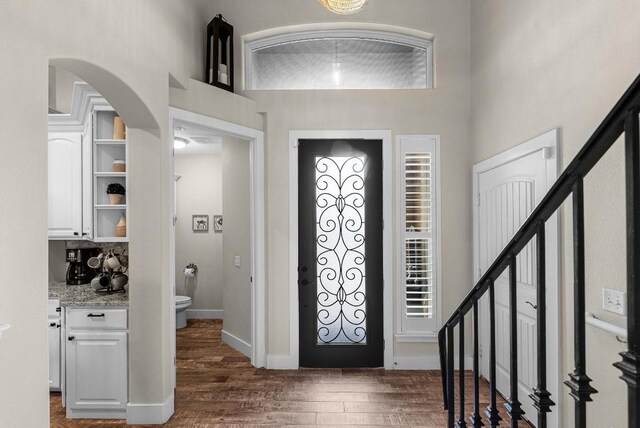 entryway with dark wood-style floors, stairs, and baseboards