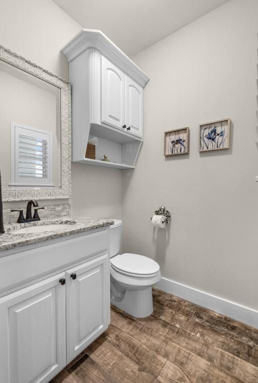 bathroom featuring vanity, wood finished floors, toilet, and baseboards